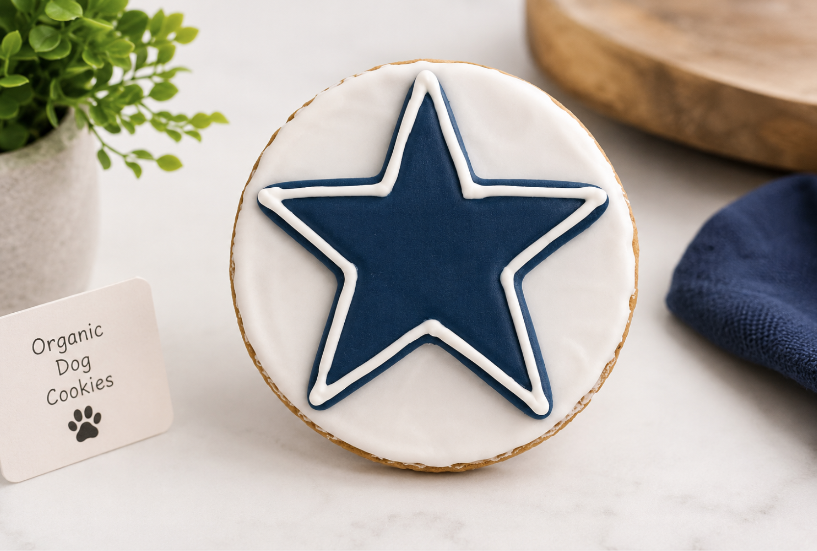 Hand-decorated Dallas Cowboys dog cookie featuring a blue star on white icing, crafted with organic peanut butter and photographed in a professional game-day themed display.