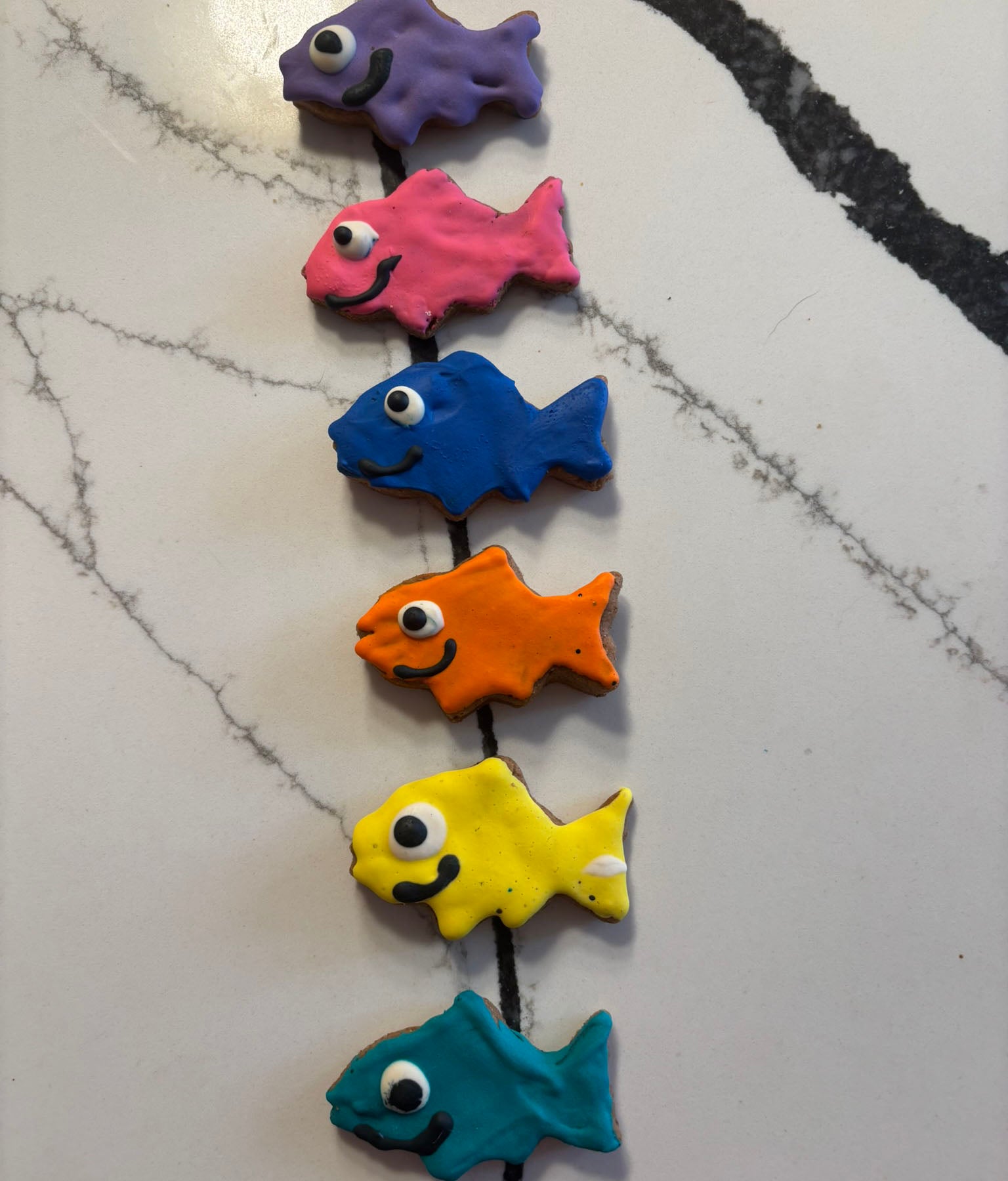 Colorful fish-shaped PAWaquarium dog treats made with organic peanut butter and cinnamon.