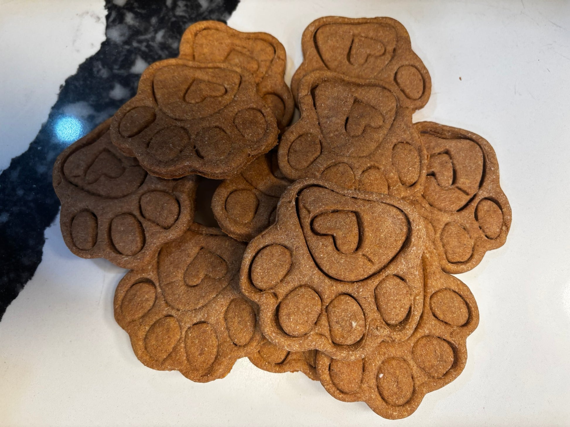Stack of organic paw-shaped dog cookies, handmade natural dog treats with paw print design