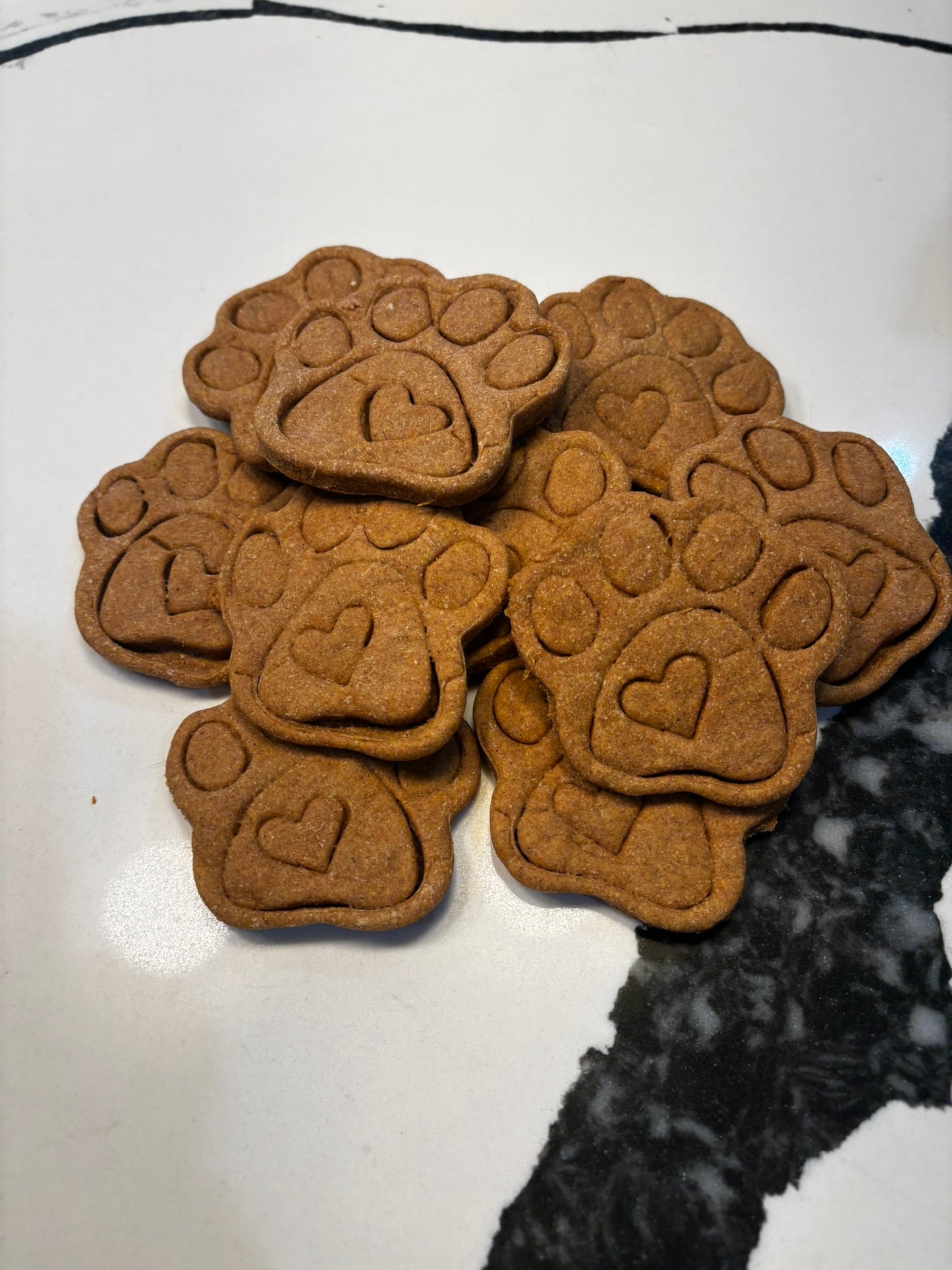 Stack of organic paw-shaped dog cookies, handmade natural dog treats with paw print design