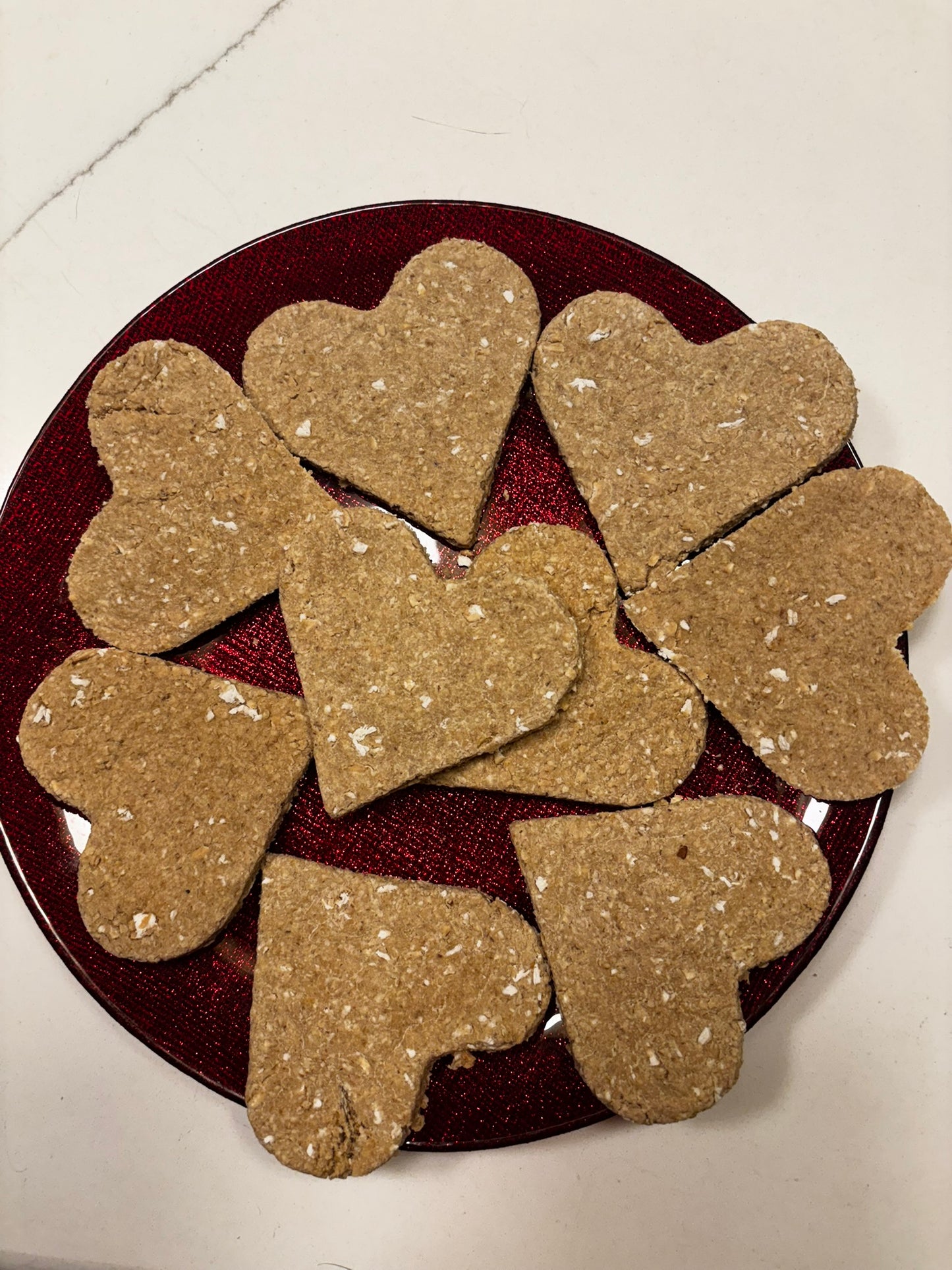 Heart-shaped organic pear dog cookies made with oat flour on red plate