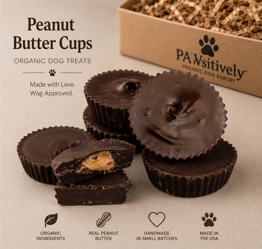 Handcrafted organic peanut butter cup dog treats stacked in a professional bakery-style display. The treats feature a rich carob coating with a creamy peanut butter center and are presented alongside PAWsitively Organic Dog Bakery branding, highlighting organic ingredients, handmade craftsmanship, and USA-made quality. 🐾🥜🍫