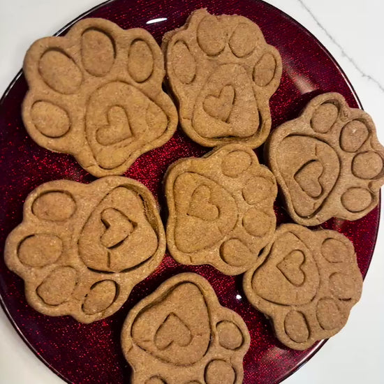 Organic paw print dog cookies with heart detail on red plate, handmade all-natural dog treats